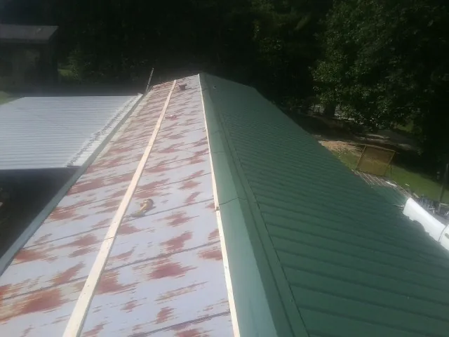 Old rusted panels beside newly installed green metal roofing — Wind Damage Roof Repair by Roofing Brothers in Joppa