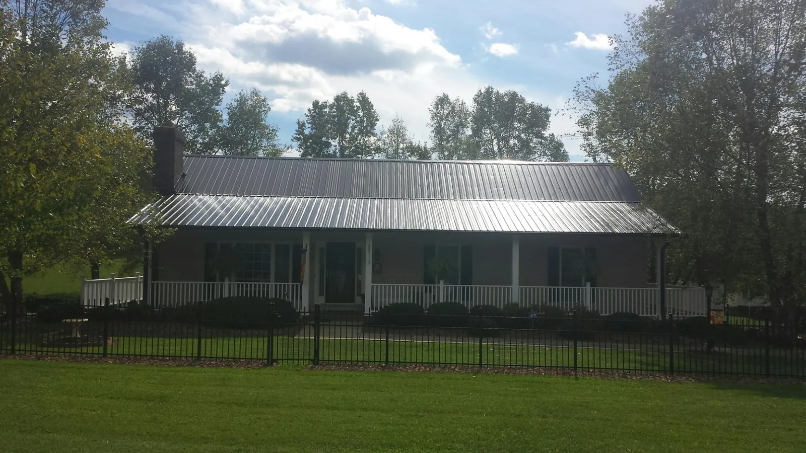 Gray metal roof on a brick ranch with a full width front porch — Gutter Guard Installation work by our crew in Joppa