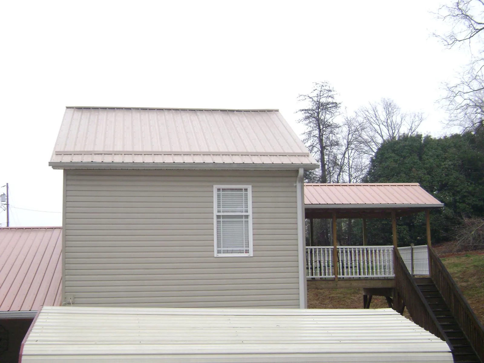 Tan metal roofs on a two story addition and attached porch, from a Roof Replacement job in Joppa