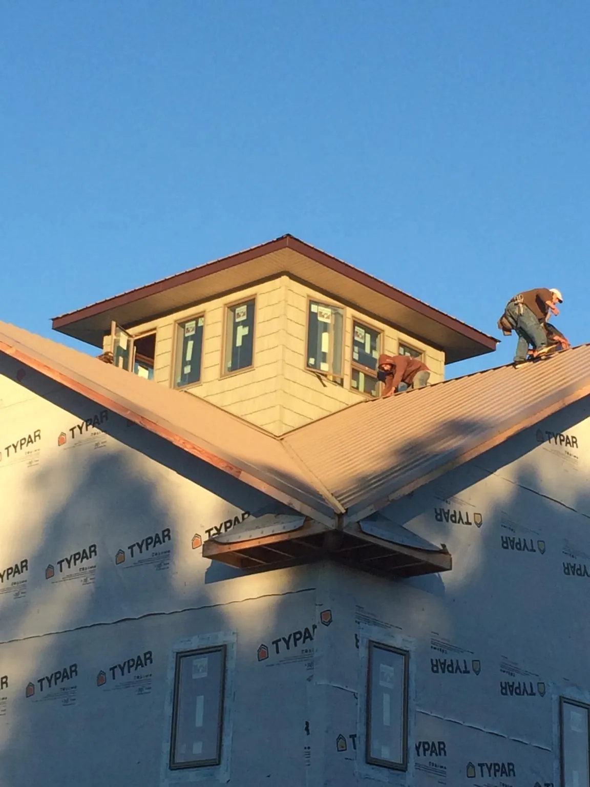Roofers working around a rooftop cupola on a new metal roof at sunset — Roof Waterproofing in Joppa by Roofing Brothers